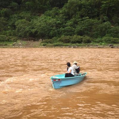 Dos personas se encuentran en una balsa, el rio se muestra crecido y muy sucio